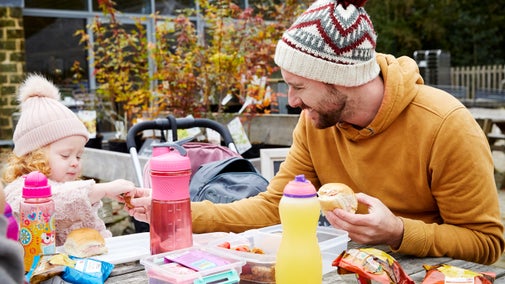 A man and a child outside the cafe and shop in October with a picnic at Stourhead, Wiltshire 1522283